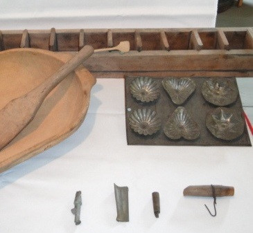 Sugaring moulds, tin and wood, and spouts. 
This wooden maple sugar mould would have been filled with sugar, each space making a one pound block. 
(Compton County Museum Collection / Photo - Jackie Hyman)