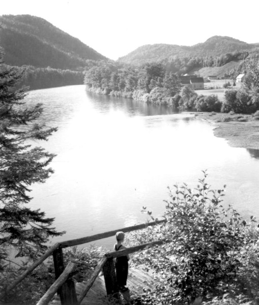 A young boy looking down at the river from Salmon Lodge Fishing Camp, c.1940s. (Photo - Cascapedia River Museum Collection)
